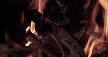 Şömine odunu ısınmak için yanıyor, ateş çatırdıyor ve alevler yanıyor.