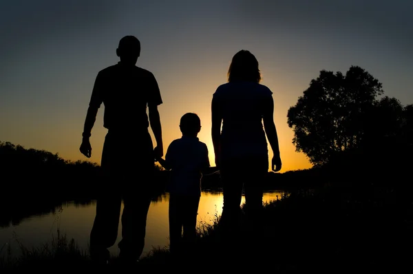 Äiti, isä ja lapsi siluetteja auringonlaskun aikaan — kuvapankkivalokuva