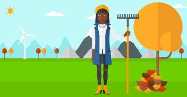 Woman with rake near tree and heap of leaves.