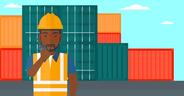 Stevedore стоит на фоне грузовых контейнеров . — стоковый вектор