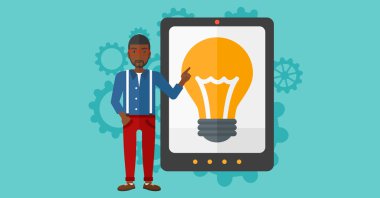 Man pointing at tablet computer with light bulb on screen.