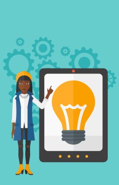 Woman pointing at tablet computer with light bulb on screen.