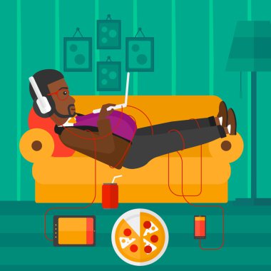 Birçok gadget'lar ile kanepede yatan adam.