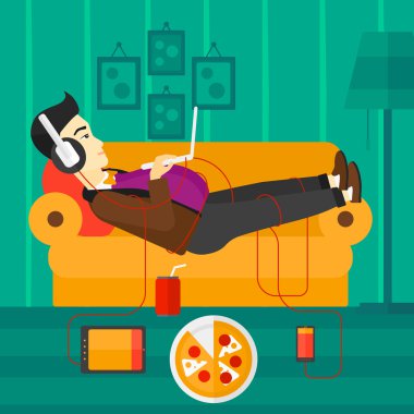 Birçok gadget'lar ile kanepede yatan adam.