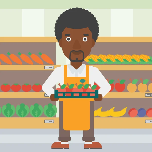 Supermarkt werknemer met een doos vol met appels. — Stockvector