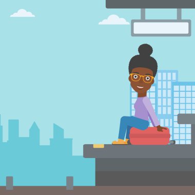 Woman sitting on suitcase at the train station.