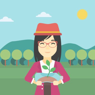 Plastik şişede büyüyen bitki tutan kadın.