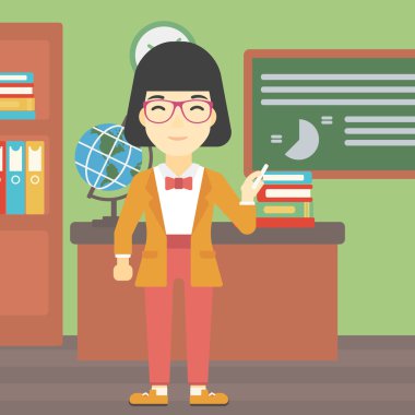 Öğretmen elinde tebeşir ile yazı tahtası önünde.