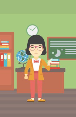 Öğretmen elinde tebeşir ile yazı tahtası önünde.