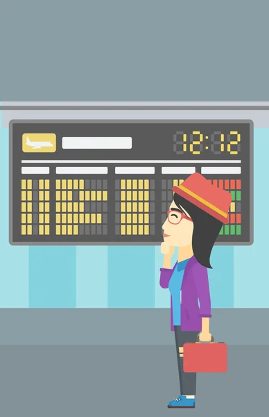 Mujer mirando la tabla de horarios en el aeropuerto . — Vector de stock