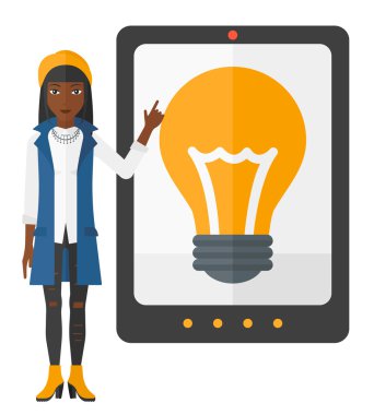 Woman pointing at tablet computer with light bulb on screen.