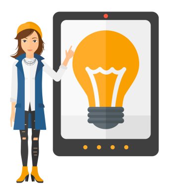 Woman pointing at tablet computer with light bulb on screen.