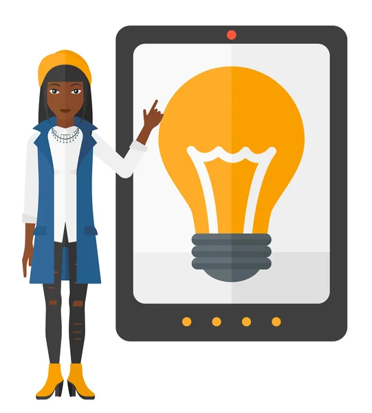 Woman pointing at tablet computer with light bulb on screen. — Stockvector