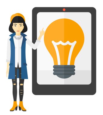 Woman pointing at tablet computer with light bulb on screen.