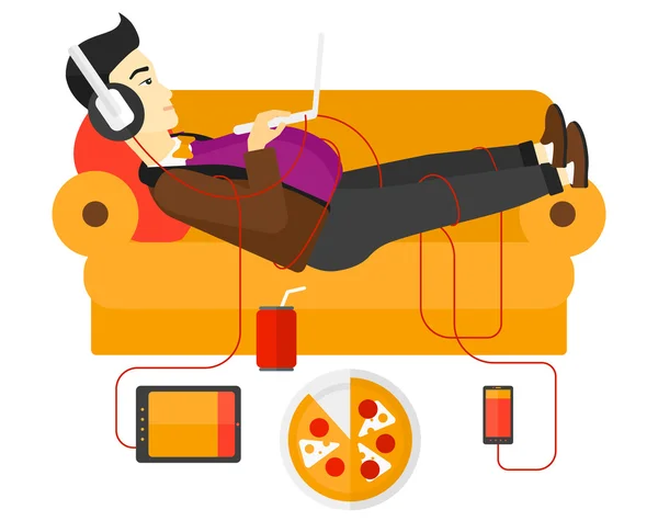 Hombre con gadgets acostado en el sofá . — Vector de stock