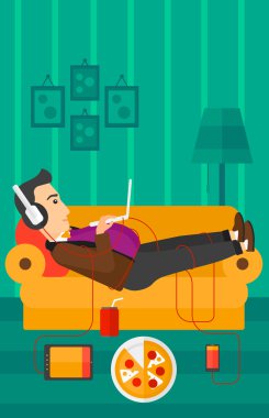 Birçok gadget'lar ile kanepede yatan adam.