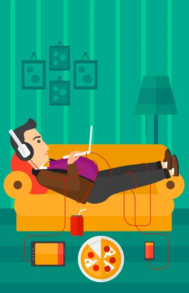 Homem deitado no sofá com muitos gadgets . —  Vetores de Stock
