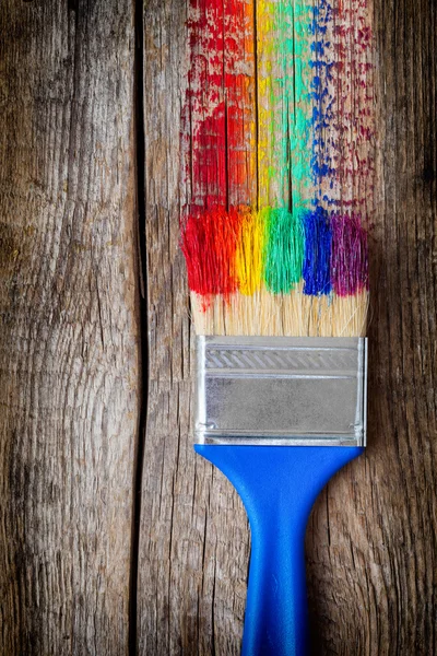 Pinceles y pinceladas multicolor de arcoíris sobre tabla de madera — Foto de Stock