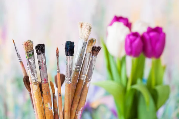 Artistieke verfborstels, boeket tulpen en schilderen achtergrond — Stockfoto