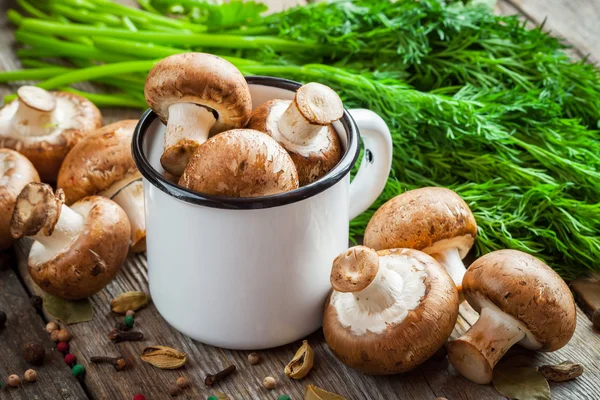 Paddestoelen champignons in mok, dille en kruiden op houten tafel. — Stockfoto