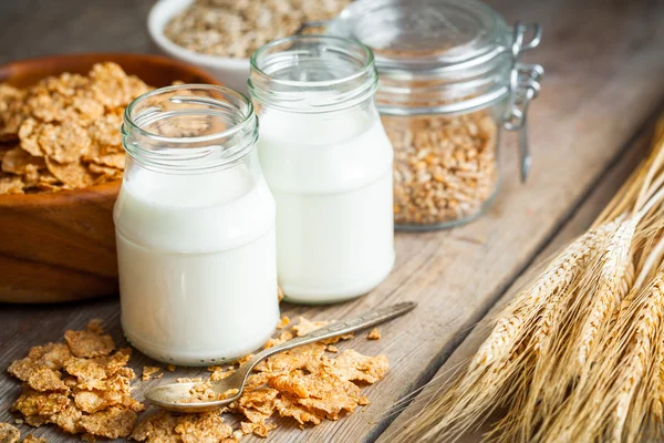 Pequeno-almoço cereais flocos de trigo, espigas e garrafas de leite — Fotografia de Stock