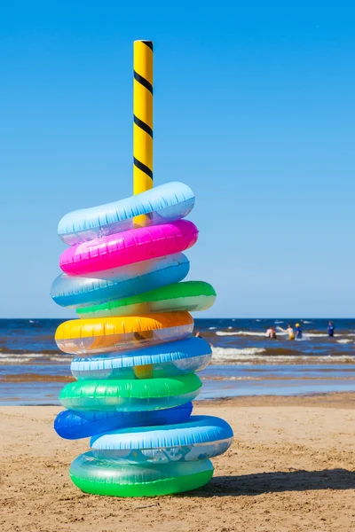 Stack av färgglada simning ringar på stranden — Stockfoto