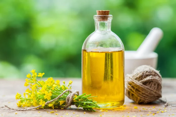 Flaska rapsolja (canola) och uppre blommor på bord — Stockfoto