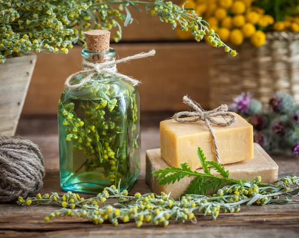 Bottle of tarragon tincture, healthy herbs and bars of soap — Stock Photo, Image