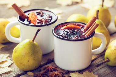 Mulled wine in white rustic mugs with spices and pear fruits.  clipart