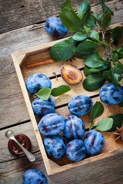 Ciruelas frescas en caja de madera y tarro de mermelada de frutas. Vista superior —  Fotos de Stock