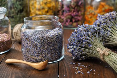 Bitki çayı yapmak için bir kavanoz kuru lavanta çiçeği ve kuru lavanta. Arka planda kurumuş şifalı bitkiler var. Alternatif tıp.