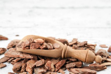 Beyaz tahta üzerinde çam kabuğu ve kırsal ahşap kepçe.