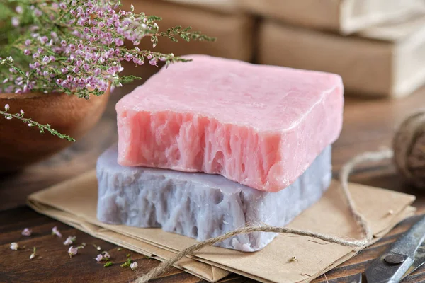 Ev yapımı sabunluklar ve funda çiçekleri. Arka planda ambalaj kağıdında organik sabun çubukları.