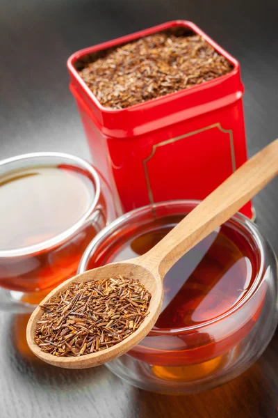 Rooibos en cuchara de madera, dos tazas de té y caja de lata de té — Foto de Stock