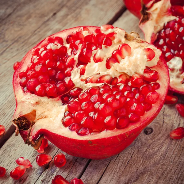 Sepotong buah delima matang dan butiran merah di meja kayu — Stok Foto