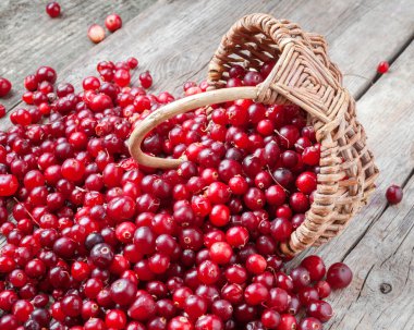 Fresh red cranberries and berries  in basket on old table clipart