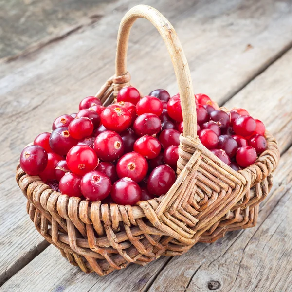 Frische rote Preiselbeeren im Weidenkorb auf rustikalem Tisch — Stockfoto