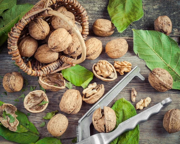 Nueces, cascanueces y cesta en la mesa vieja, vista superior . — Foto de Stock