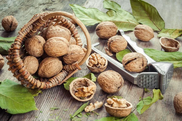 Орехи, орехи и корзина на старом деревянном столе — стоковое фото