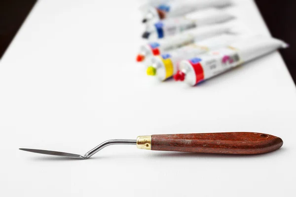 Paleta faca closeup e óleo tubos de pintura multicolor no ar branco — Fotografia de Stock