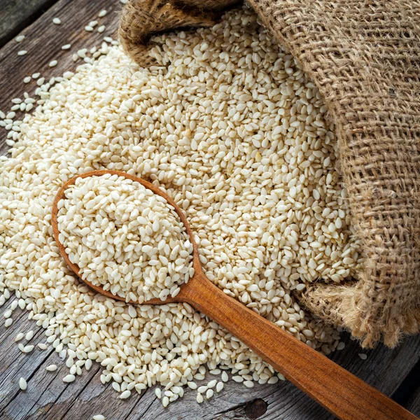 Sesame seeds in wooden spoon on wooden rustic table — Stock Photo, Image