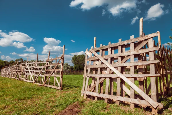 Dřevěný rustikální plot, modrá obloha a vesnici na šířku — Stock fotografie