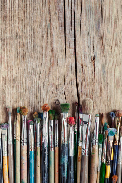 row of artist paintbrushes on old wooden rustic table