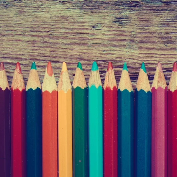 Row of colored drawing pencils closeup on old desk. — Stock Photo, Image