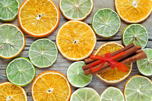 Сушені апельсинові, лимонні скибочки та палички кориці на дерев'яному столі . — стокове фото