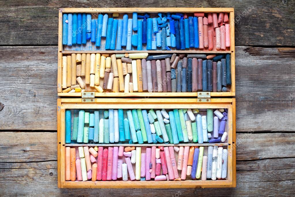 Set of multicolored pastel crayons in open wooden artist box on Stock