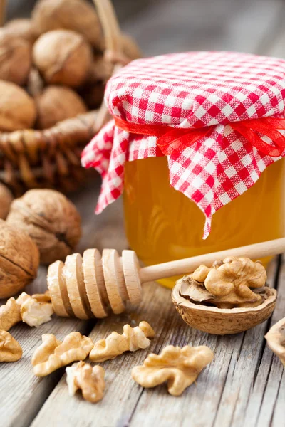 Miel en tarro, nuez en canasta sobre fondo sobre tabla de cocina vieja — Foto de Stock