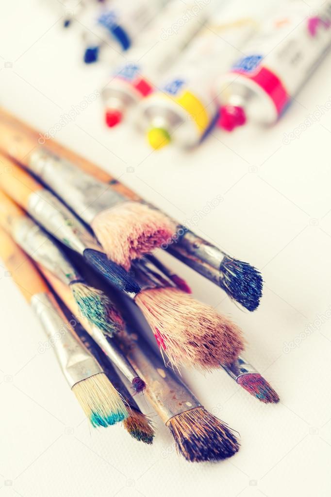 paintbrushes closeup and oil multicolor paint tubes on white art