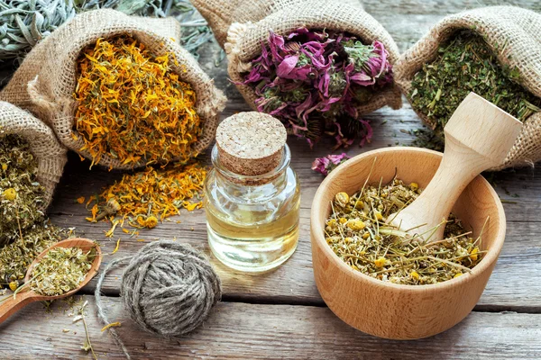 Healing herbs in hessian bags, mortar with chamomile and essenti — Stock Photo, Image