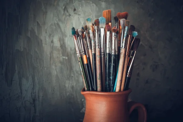 Paintbrushes in a jug from potters clay. — Stock Photo, Image